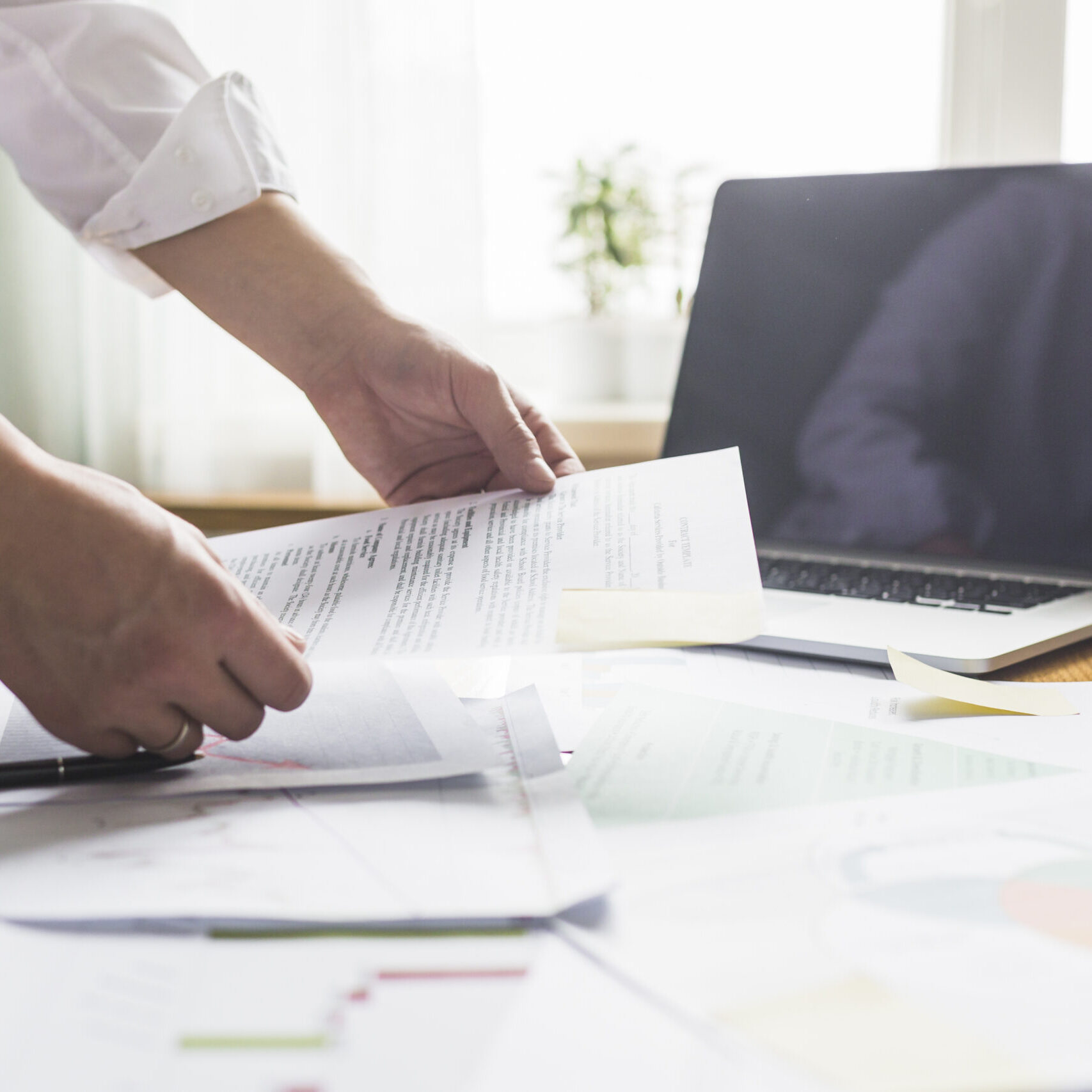 businessperson-s-hand-holding-document-wooden-desk